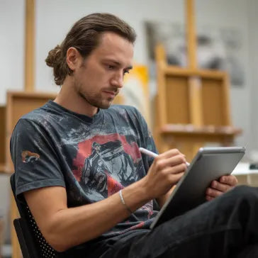 Hombre usando tableta digital en estudio de arte, dibujando con stylus