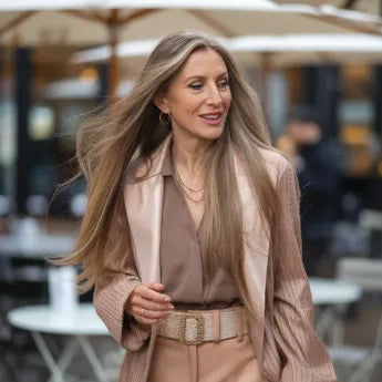 Mujer con cabello largo caminando en cafetería al aire libre, estilo casual elegante