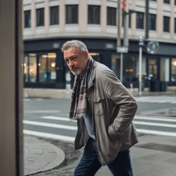 Hombre caminando en ciudad con abrigo y bufanda, estilo urbano y casual