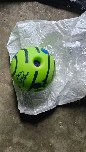 Pelota verde para mascotas con diseño de tenis y agujero central, ideal para juegos y ejercicio